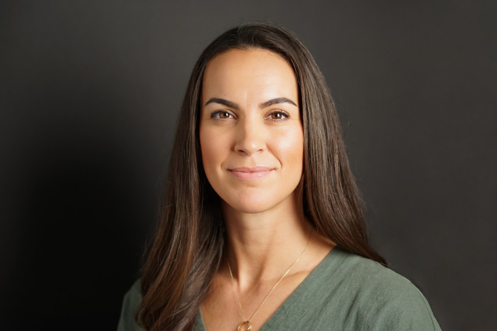 Professional headshot of brunette woman with brown eyes and tan skin wearing a green shirt who is an interior designer in Phoenix Arizona
