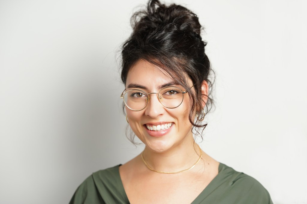 Professional headshot of a mixed race Arab woman with curly hair and glasses with a white background in Phoenix Arizona