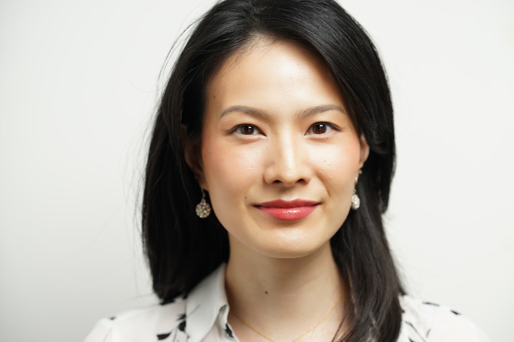 Professional headshot of a young Chinese woman smiling wearing a white shirt with a white background in Phoenix Arizona