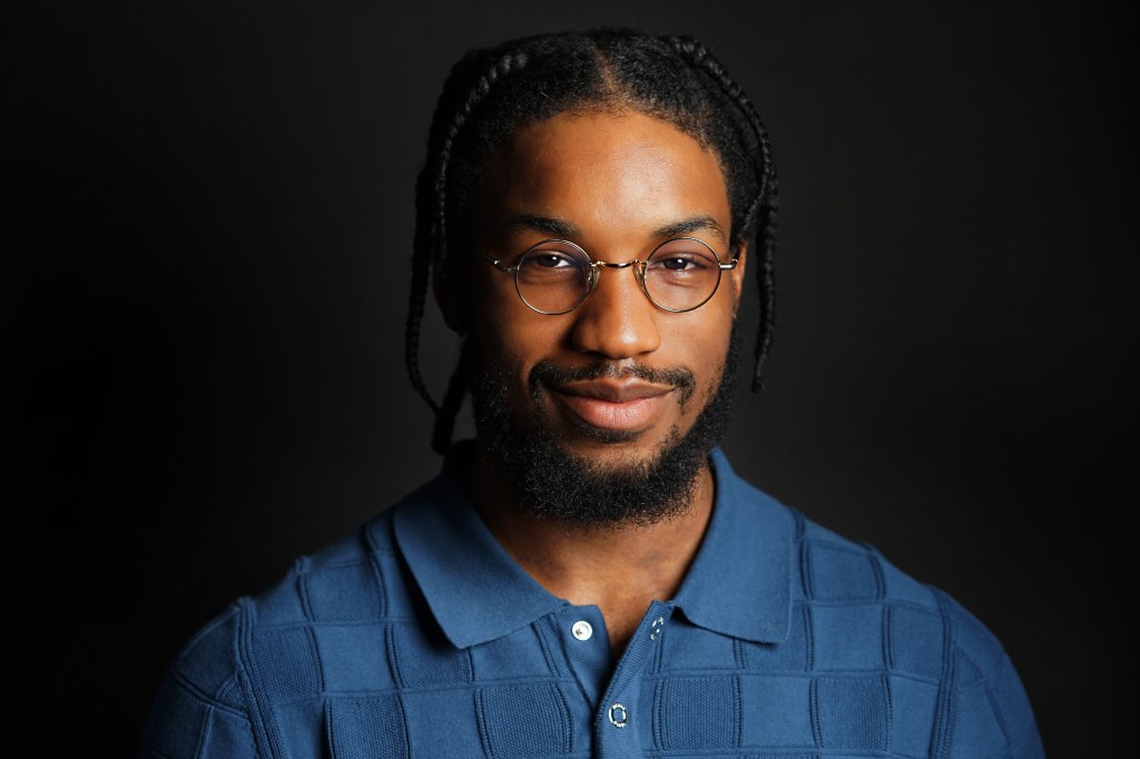 Professional headshot of a young Black man wearing a blue shirt with black background in Phoenix Arizona